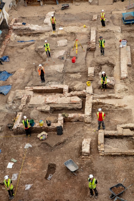 An aerial view of an excavation site full of workers and stone walls.