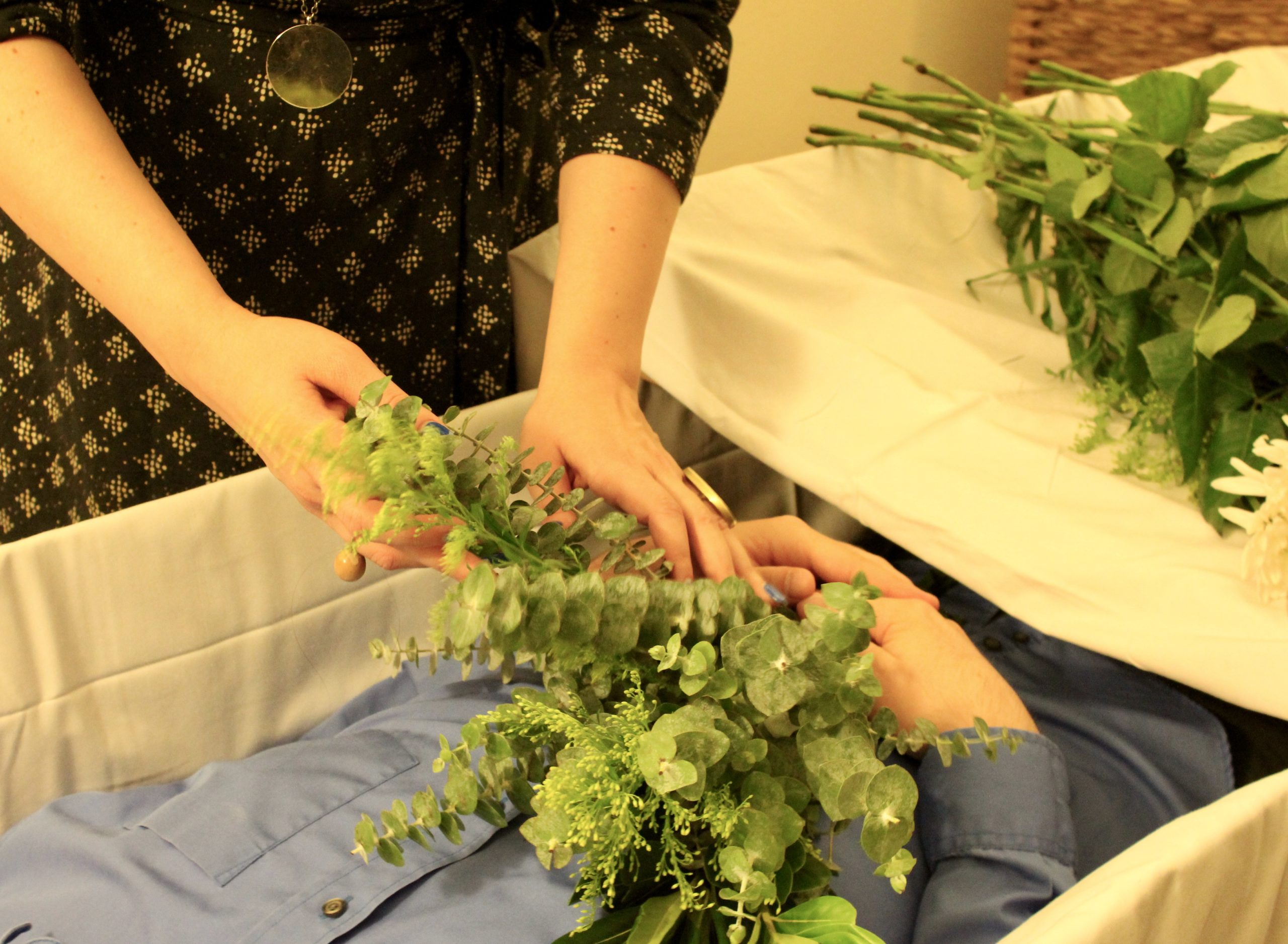 A pair of hands arranges some flowers on a body