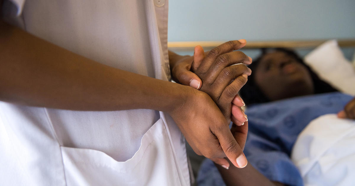 Photo of a death doula holding the hand of a death patient