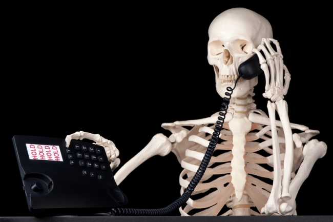 Photo of a skeleton using a telephone.
