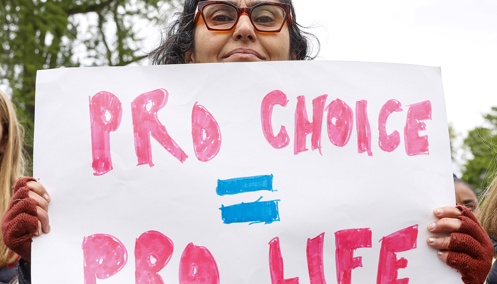 close up photograph of woman holding a sign that reads 