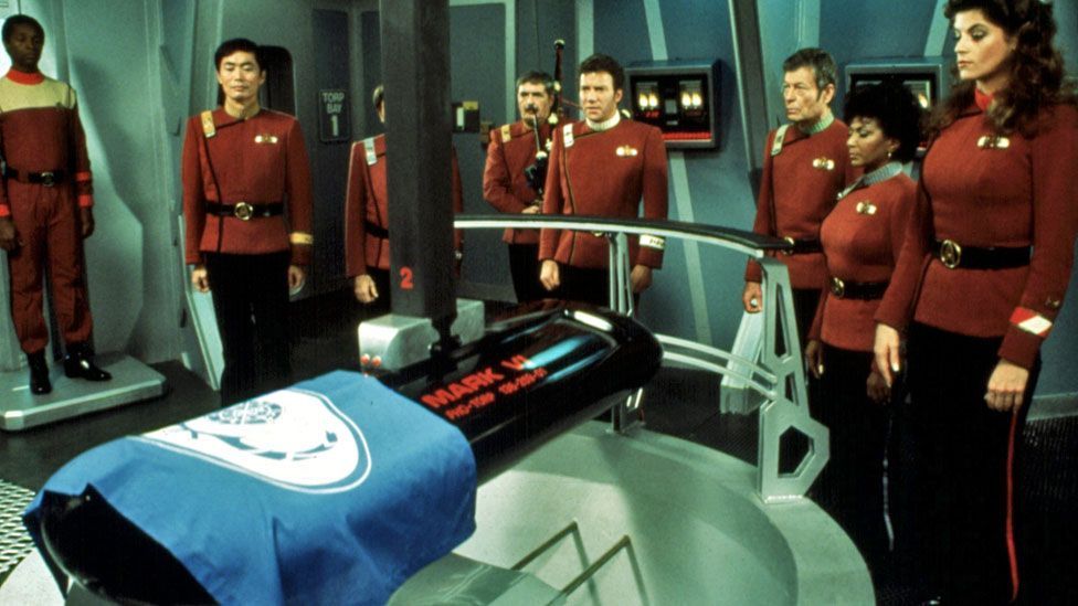 Screen shot from 1982 Star Trek film The Wrath of Kahn. The crew of the Enterprise stand around Spock's coffin.