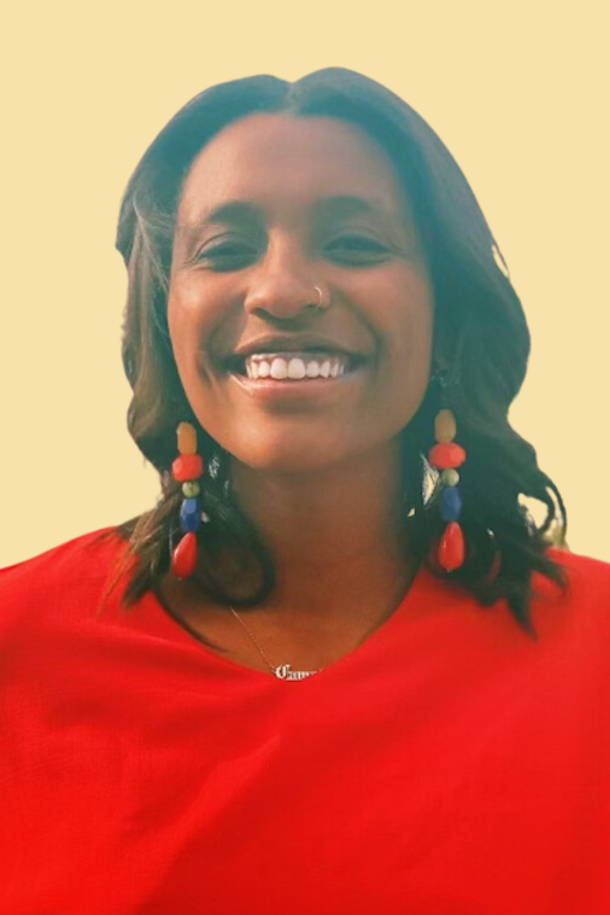 Woman wearing bright red shirt and long earrings smiling to camera