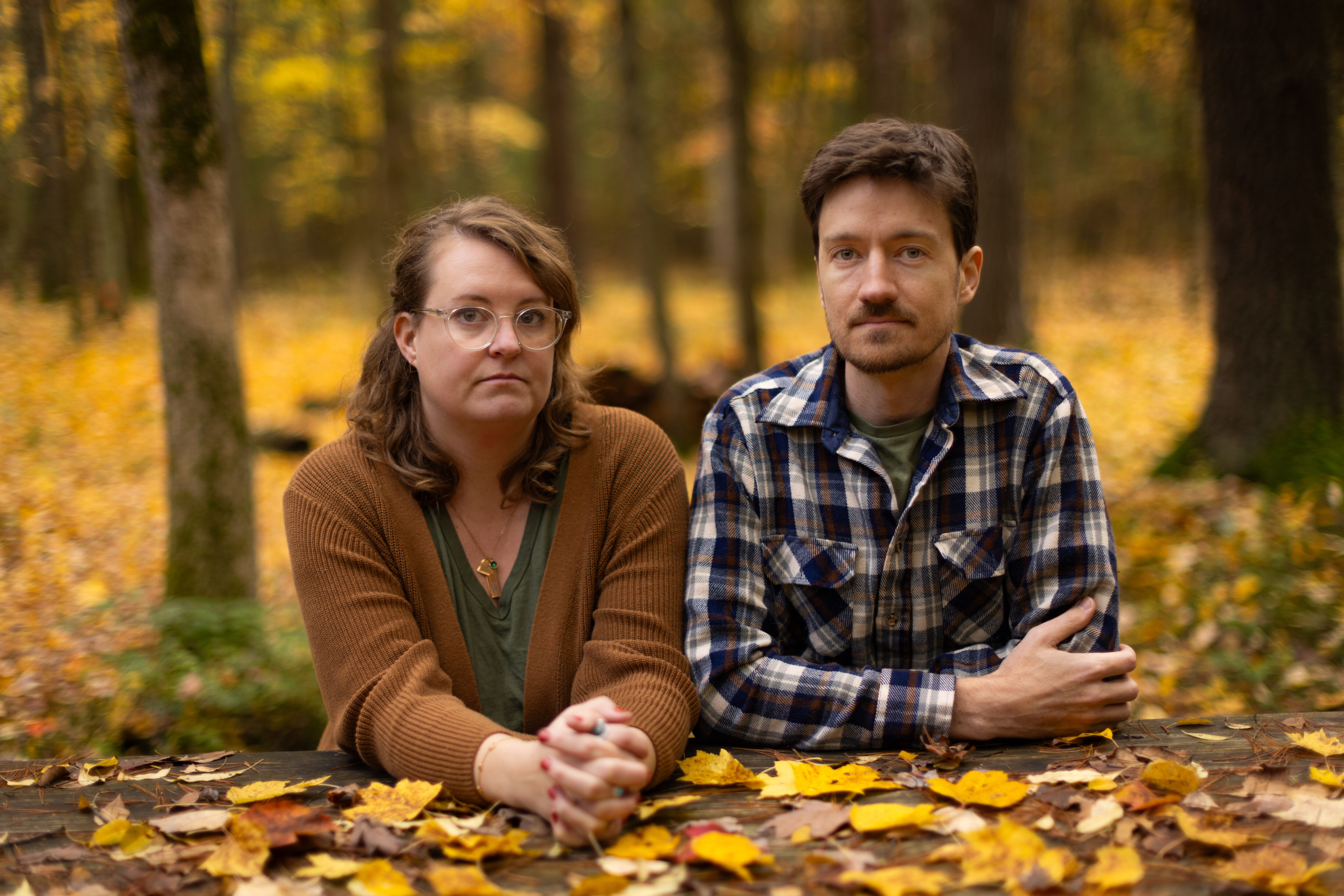 Annica and Peter in the burial forest during fall, surrounded by tress and fallen leaves in a variety of colors