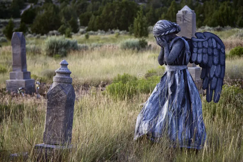 weeping angel statue in an overgrown cemetery