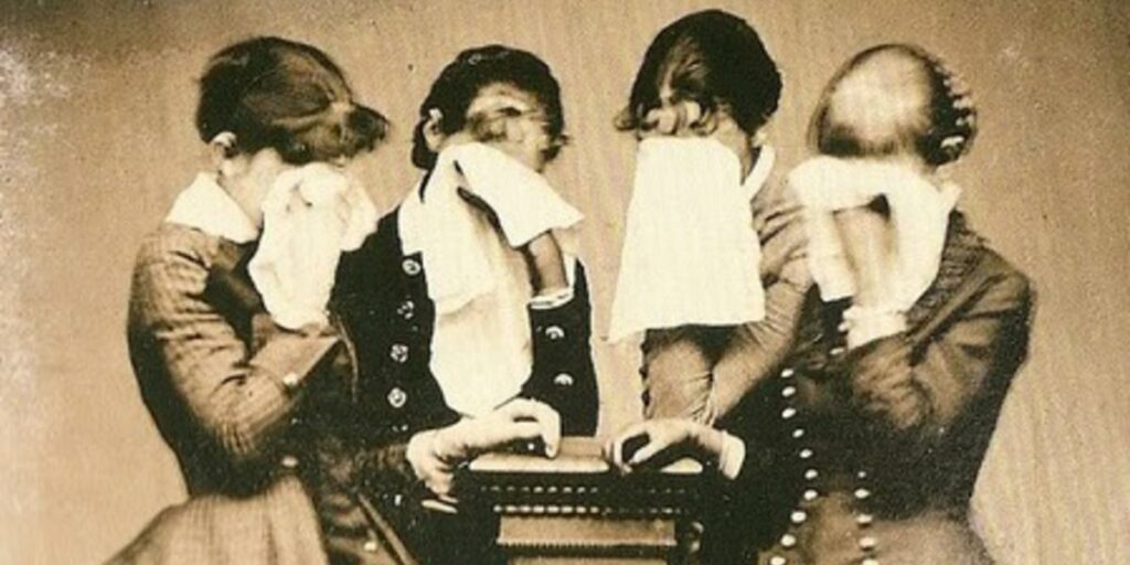 black and white Victorian era photograph of four womne in mourning, all weeping and holding handkerchifs up to the faces