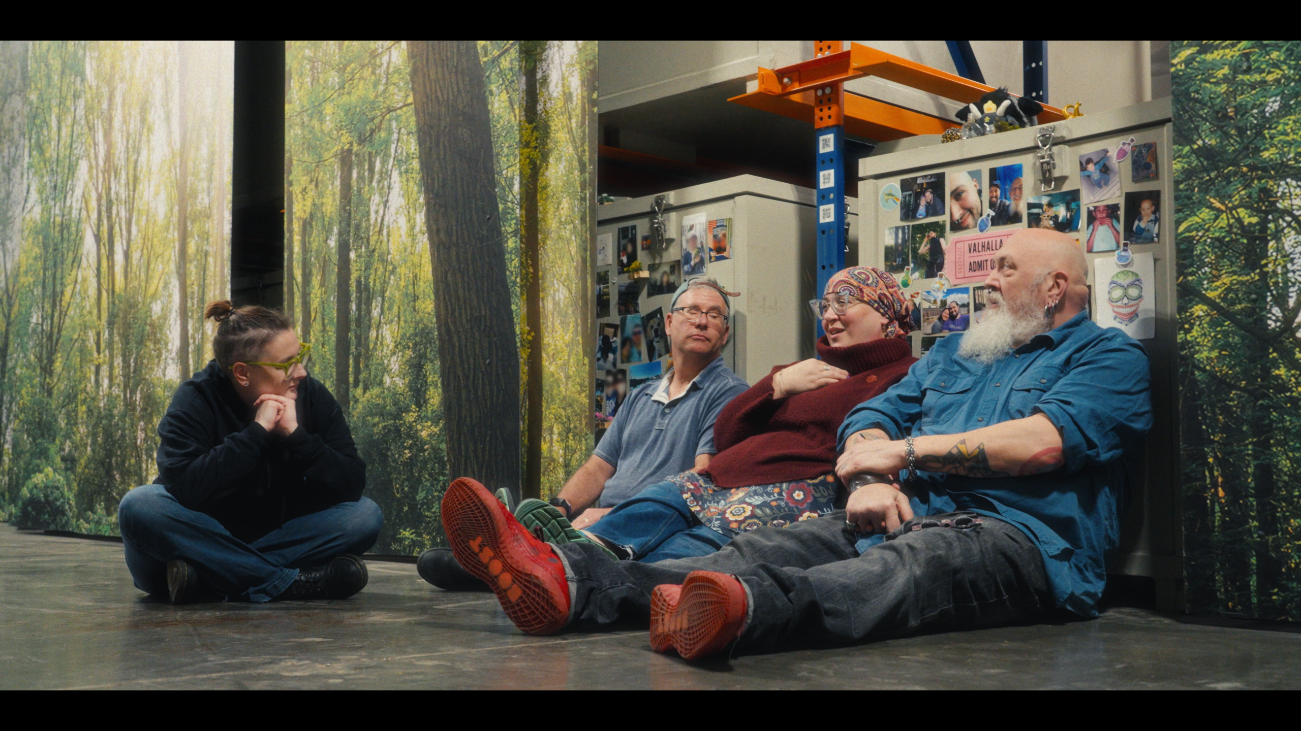 Photo still from the documentary The Life We Leave, featuring four people sitting on the floor with human composting vessels at Return Home in Seattle, Washington